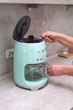 Kemerovo. - Rusya. 16 Mayıs 2022. Bir kadının elleri mutfak masasındaki KOBİ marka kahve makinesine kahve döküyor..