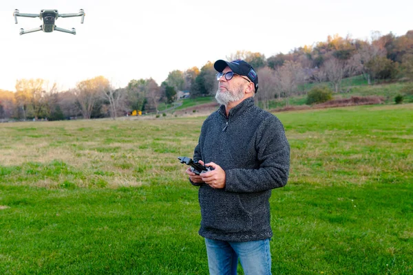 an adult man with a beard launches a drone into the sky. Holds the remote control and watches the flight.