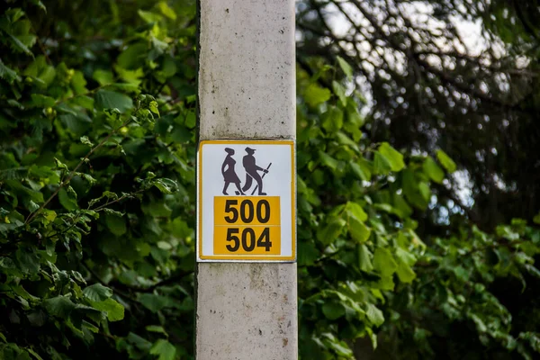 close-up of a sign of hiking trails on a concrete pillar with a route numbers