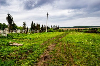Eski köy mezarlığı ve ekilebilir tarla arasında kırsal bir yol var.