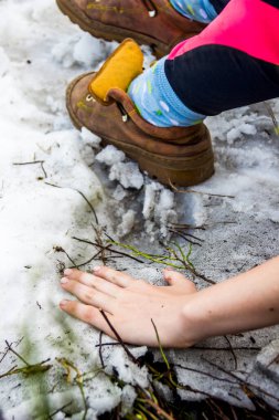 Dağların karlı zirvesinde kadın eli ve bacaklarının yakın çekimi.