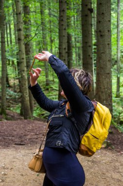 Bir kadın akıllı telefonuyla ormanın fotoğrafını çekiyor.