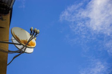 Çatının altındaki duvarda paslı nokta olan iki beyaz uydu anteni.