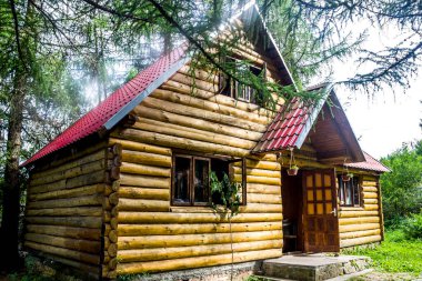 a small wooden house with red roof in Ukrainian Carpathian forest