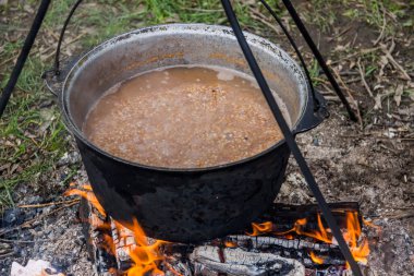 Kamp ateşinde karabuğday lapası ile pişirilen siyah kazanın yakın çekimi.