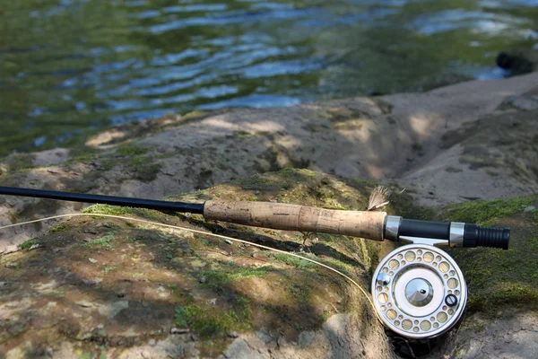 Flyfishing rod on the stone by the river Royalty Free Stock Images
