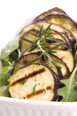 taze biberiye ile bir tabak ızgara patlıcan dilimleri