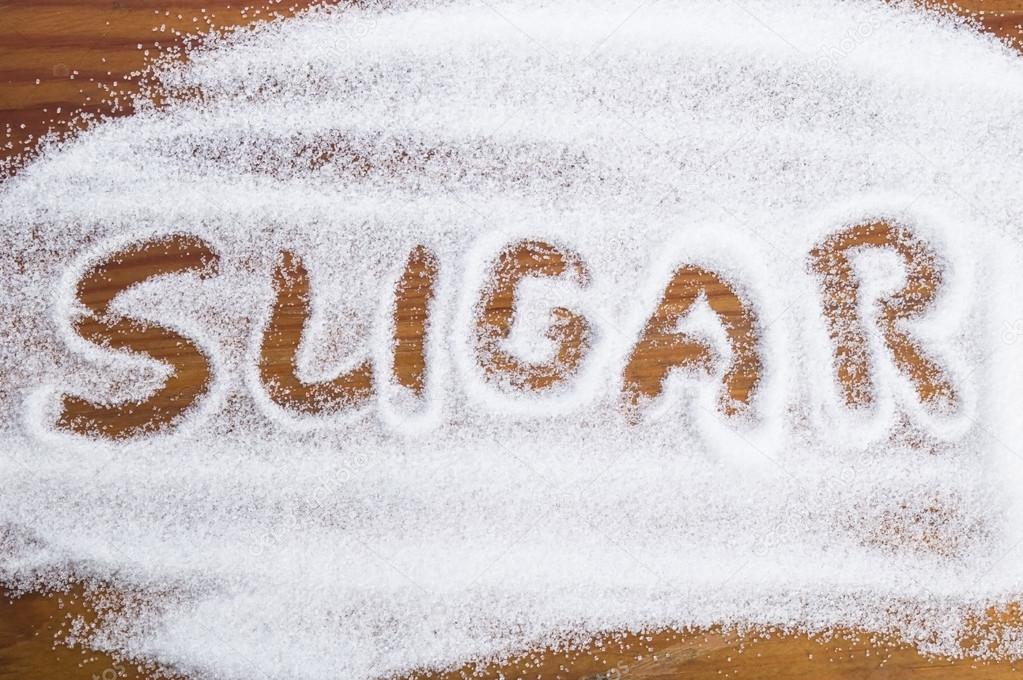 The word sugar written into a pile of white granulated sugar — Stock