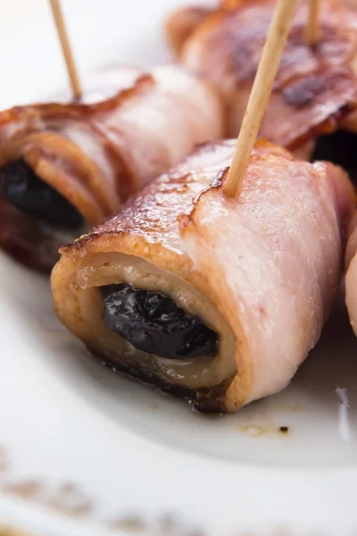 Bakade katrinplommon i bacon på en tallrik — Stockfoto