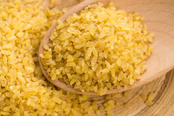 Trigo bulgur en cuchara de madera — Foto de Stock