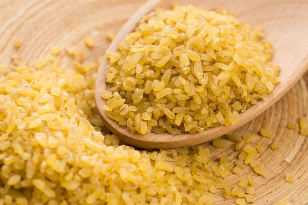 Trigo bulgur en cuchara de madera — Foto de Stock