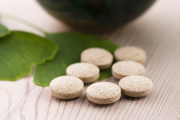 Ginkgo biloba leaves in mortar and pills — Stock Photo, Image