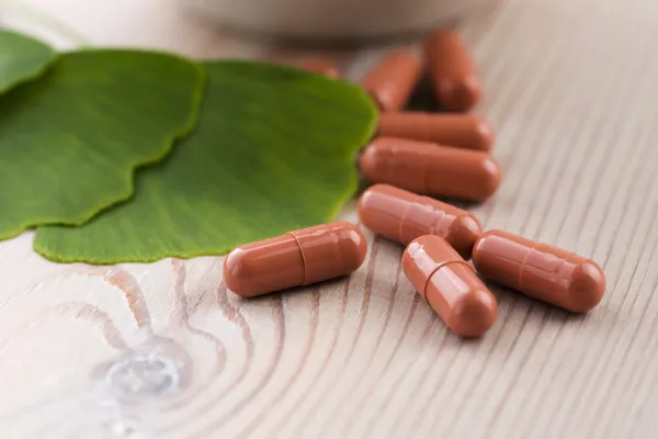 Ginkgo biloba leaves in mortar and pills — Stock Photo, Image