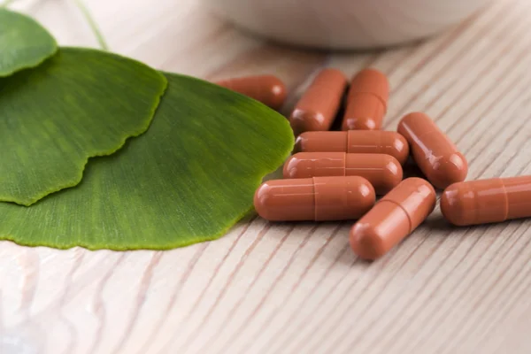 Ginkgo biloba leaves in mortar and pills — Stock Photo, Image