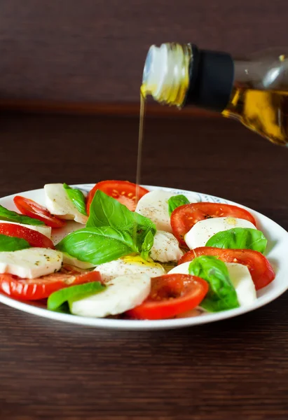 Caprese-Salat mit eingießendem Olivenöl — Stockfoto