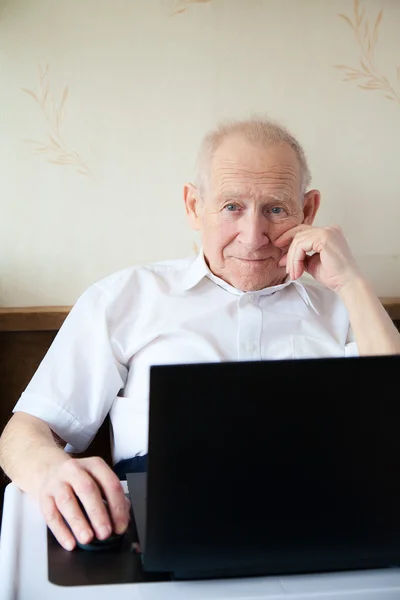 Viejo sonriente trabajando en una computadora —  Fotos de Stock