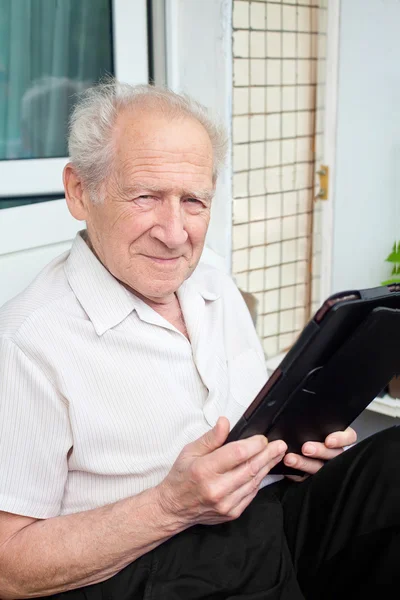 Homem sênior segurando um touchpad PC em suas mãos — Fotografia de Stock