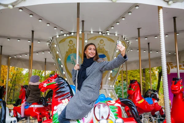 Smiling Young Woman Riding Horse Carousel Amusement Park Making Selfie — Stock Photo, Image