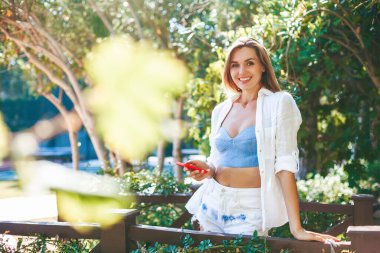 Sohbet etmek, mesaj atmak, aramak için akıllı telefonu tutan ve kullanan gülümseyen genç bir kadın. Yaşam tarzı, teknoloji ve sosyal medya ağı kavramı.