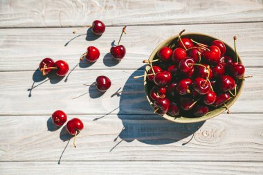 Tahta bir arka planda, olgun ve lezzetli bir kiraz kabının içinde yatıyordu.