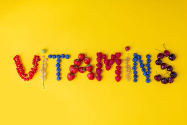 Vitaminler sarı arka planda farklı taze yaz meyvelerinden yapılmıştır.