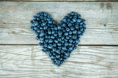 Gri ahşap arka planda kalp şeklinde yaban mersini.