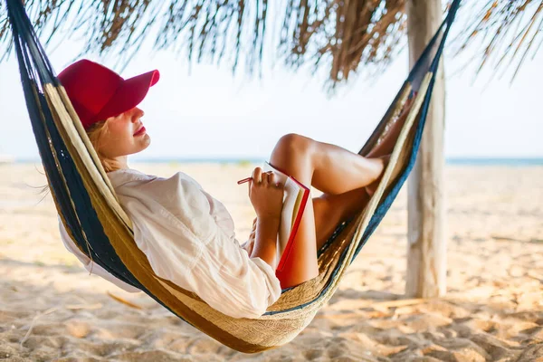 Kvinna Röd Mössa Skriver Något Sin Röda Planerare Liggande Hängmatta — Stockfoto