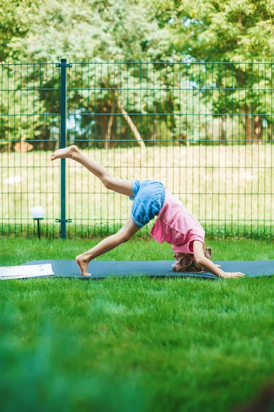 小女孩躺在滚动垫上 在公园的室外练习瑜伽 给孩子们的瑜伽孩子健康的生活方式 — 图库照片
