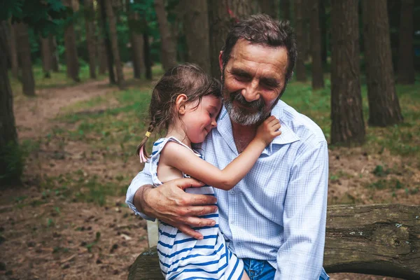 公園に座って 彼の腕の上に彼の小さな孫娘を保持髭シニア男 — ストック写真