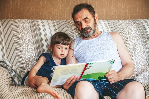 Παππούς Διάβαζε Ένα Βιβλίο Στην Εγγονή Του Καθόταν Έναν Καναπέ — Φωτογραφία Αρχείου