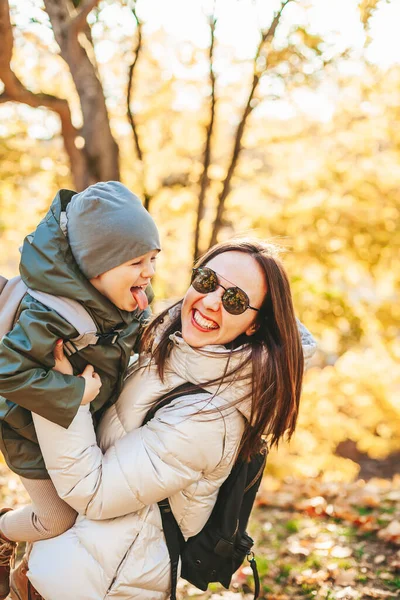 秋の公園で遊んでいる幸せな笑いの母親と小さな息子 秋の季節に外で一緒に楽しむ家族 — ストック写真