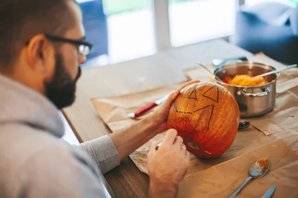 Man drawing a face for Halloween pumpkin