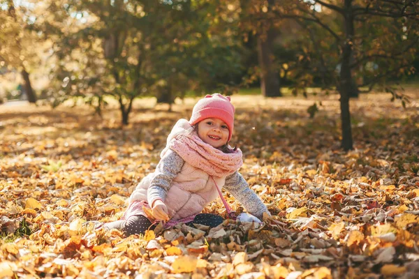 Gülümseyen Küçük Kız Sonbahar Yapraklarında Oturuyor Sonbahar Parkında Onlarla Oynuyor — Stok fotoğraf