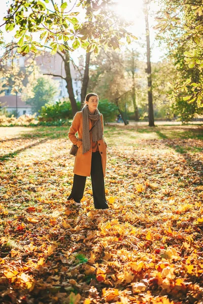 晴れた日に美しい秋の公園を歩くベージュコートの若い女性 — ストック写真