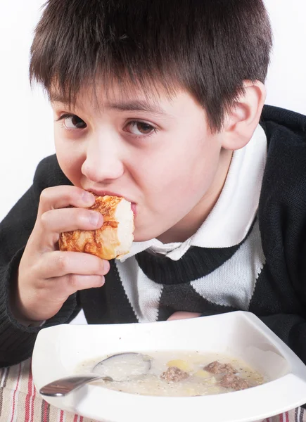 The boy eats the soup with meatballs — Stock Photo, Image