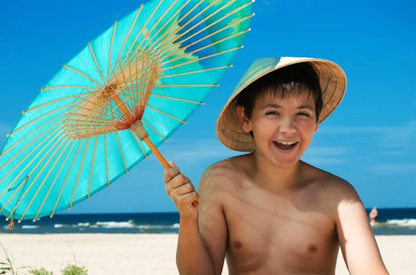 Boy with umbrella on the beach — Stock Photo, Image