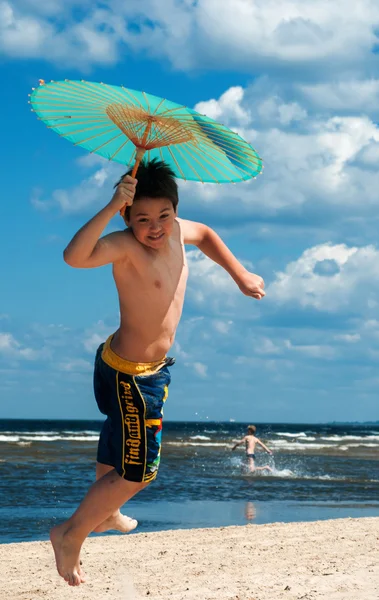 Boy with umbrella on the beach — Stock Photo, Image