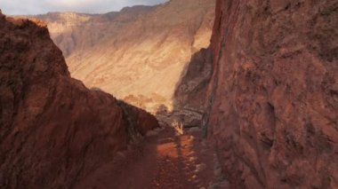 Terk edilmiş yolda kırmızı paslı taşlarla kaplı hava kulesi kırmızı kayaların arasından kaldera Las Playas 'a ve Atlantik Okyanusu kıyısına sabah güneşinin parlak ışığında kesiliyor.