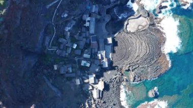 Mavi zümrüt Atlantik okyanusu ve kıyı şeridi manzaralı Pozo de Las Calcosas 'ın balıkçı köyü çatılarına göz kuşuyla dikey iniş ve Hierro' nun katı akıntılı lavlarının siyah dili.
