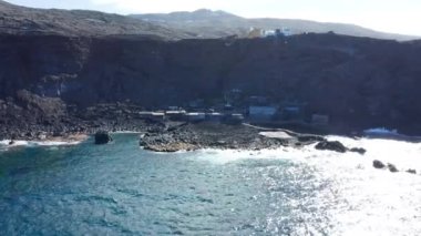 Atlantik Okyanusu 'nun üzerinde uçan doli ve katılaşmış dilin üzerinde Lav akıntısı küçük balıkçı köyü Pozo de Las Calcosas' a doğru akar. El Hierro adasının güneşine karşı gölgede kayalık koyda yer alır.