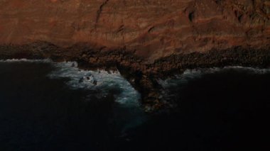 Koyu mavi Atlantik Okyanusu ve kırmızı volkanik kıyı şeridi üzerindeki hava kilitleri, El Hierro adasının güneşinin son ışınlarında öfkeli okyanus dalgalarının kırdığı düşen taşlarla doluydu.