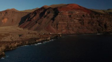 Atlas Okyanusu kıyısındaki Verodal sahiline doğru giden hava aracı El Hierro Adası, İspanya 'nın Kanarya Adaları' ndaki kayalık volkanik dağların arka planına karşı russet kumla kaplı.