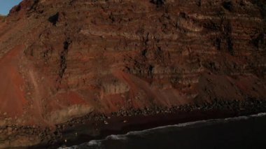 Verodal Sahili 'ne doğru kayan hava kaydırağıyla kayan taşlar ve El Hierro Adası' nın Atlantik Okyanusu 'nun tehlikeli güçlü dalgaları arasında bulunan sıcak kahverengi kumlu bir uçurum.