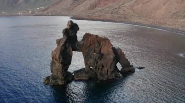 El Roque de La Bonanza 'nın ünlü kaya oluşumunu çevreleyen hava yayı, gündoğumu güneşinde, Las Playas Atlantik Körfezi' ndeki Caldera, El Hierro, Kanarya Adaları 'nın arka planına karşı çekildi.