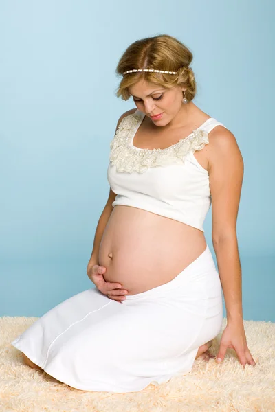 Беременная женщина сидит на коврике — стоковое фото