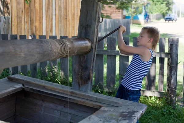 Jongen pakt een emmer met water — Stockfoto