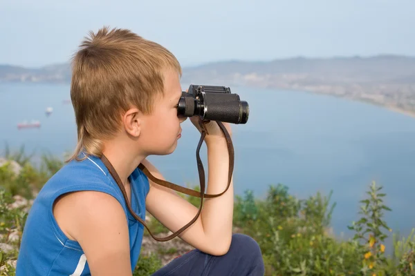 Junge blickt durch Ferngläser auf den Berg. — Stockfoto