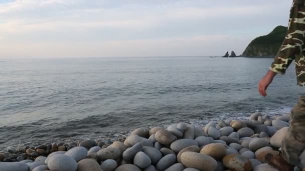 Hiker sitting on the rocky shore and looking at sea — Stock Video