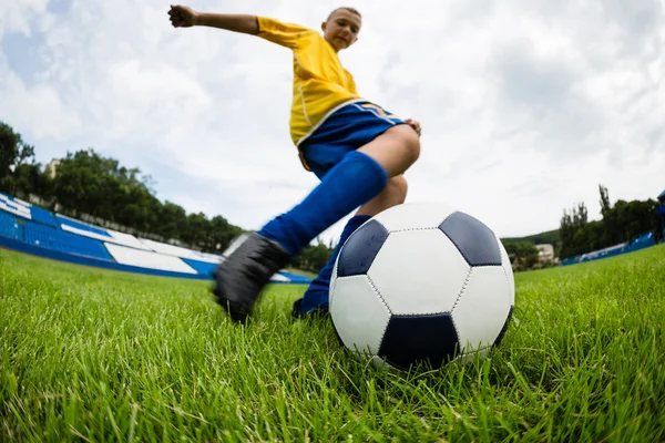 Jongen voetbalspeler raakt de bal — Stockfoto