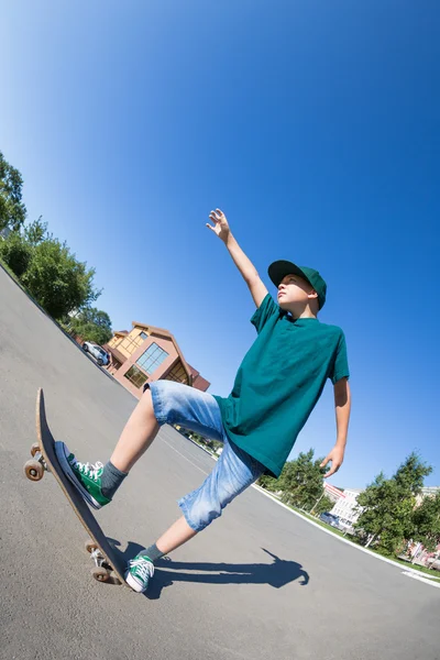 Garçon chevauchant un skateboard dans la rue . — Photo